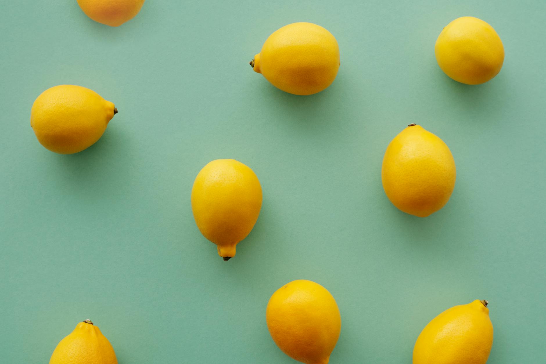 Bright yellow lemons arranged on a pastel green background, representing the lemon vibrator and clitoral pleasure.