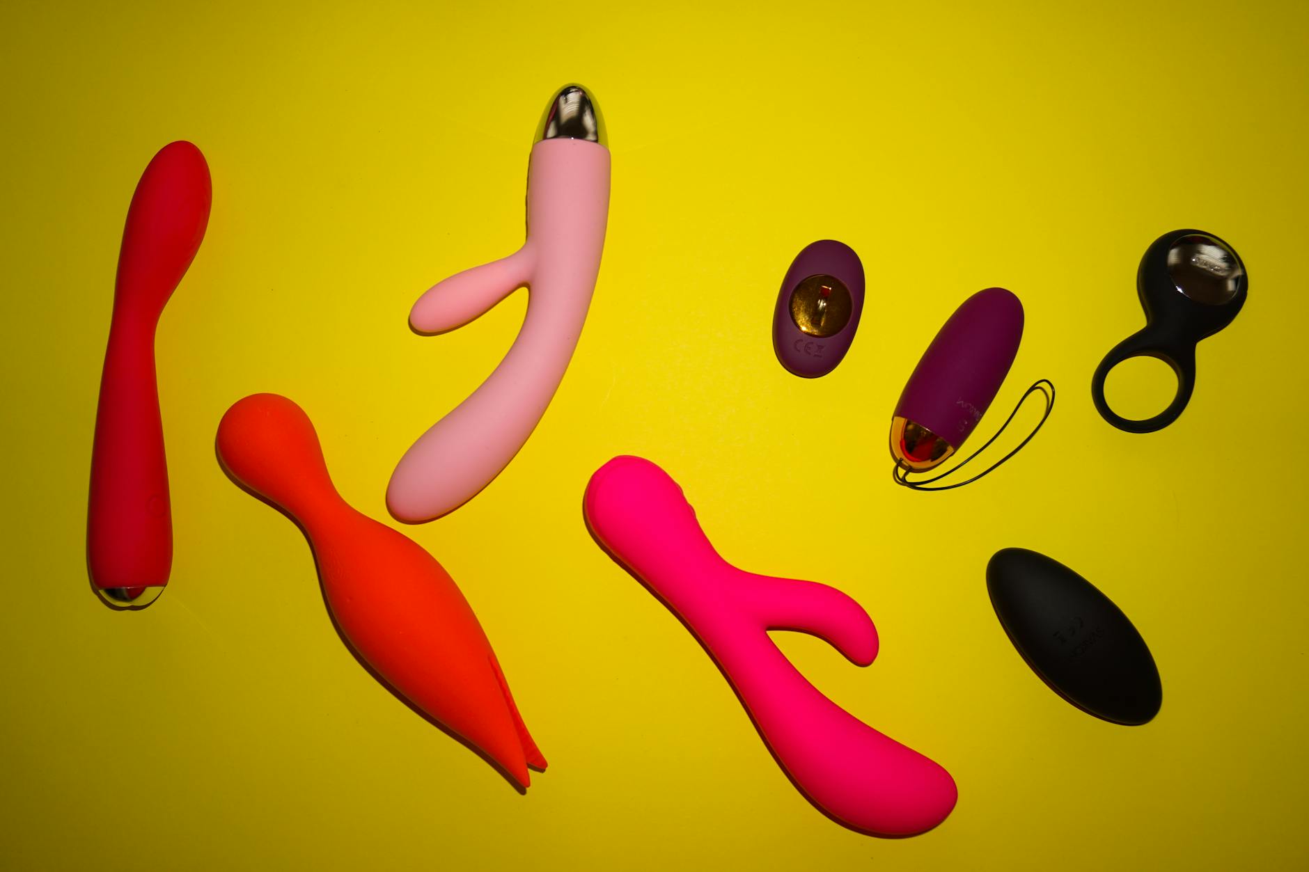Woman holding blue and pink silicone vibrators with a contemplative expression