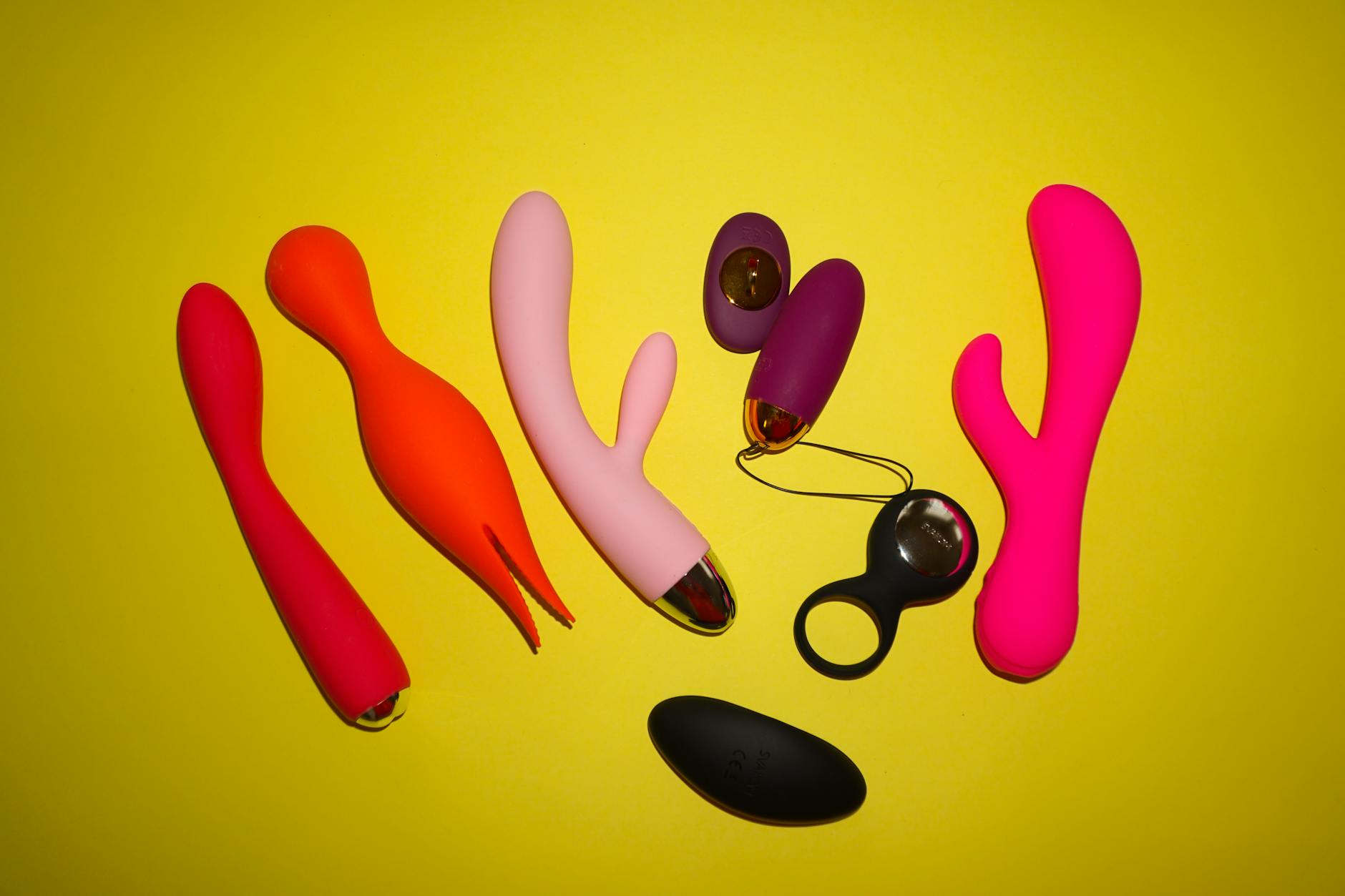 Woman holding blue and pink silicone vibrators in thoughtful consideration