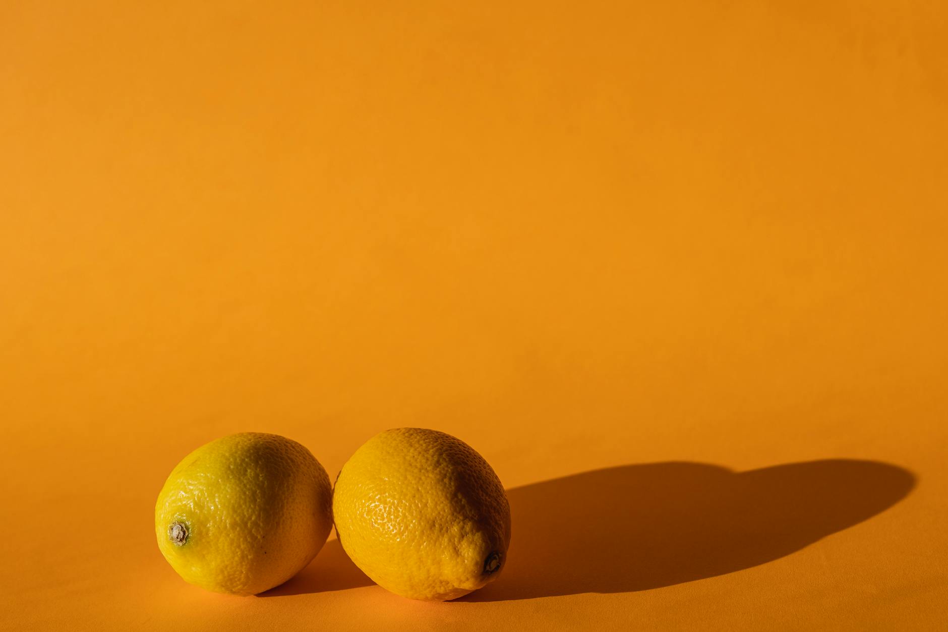 Fresh lemons on bright yellow background, symbolizing vitality and wellness
